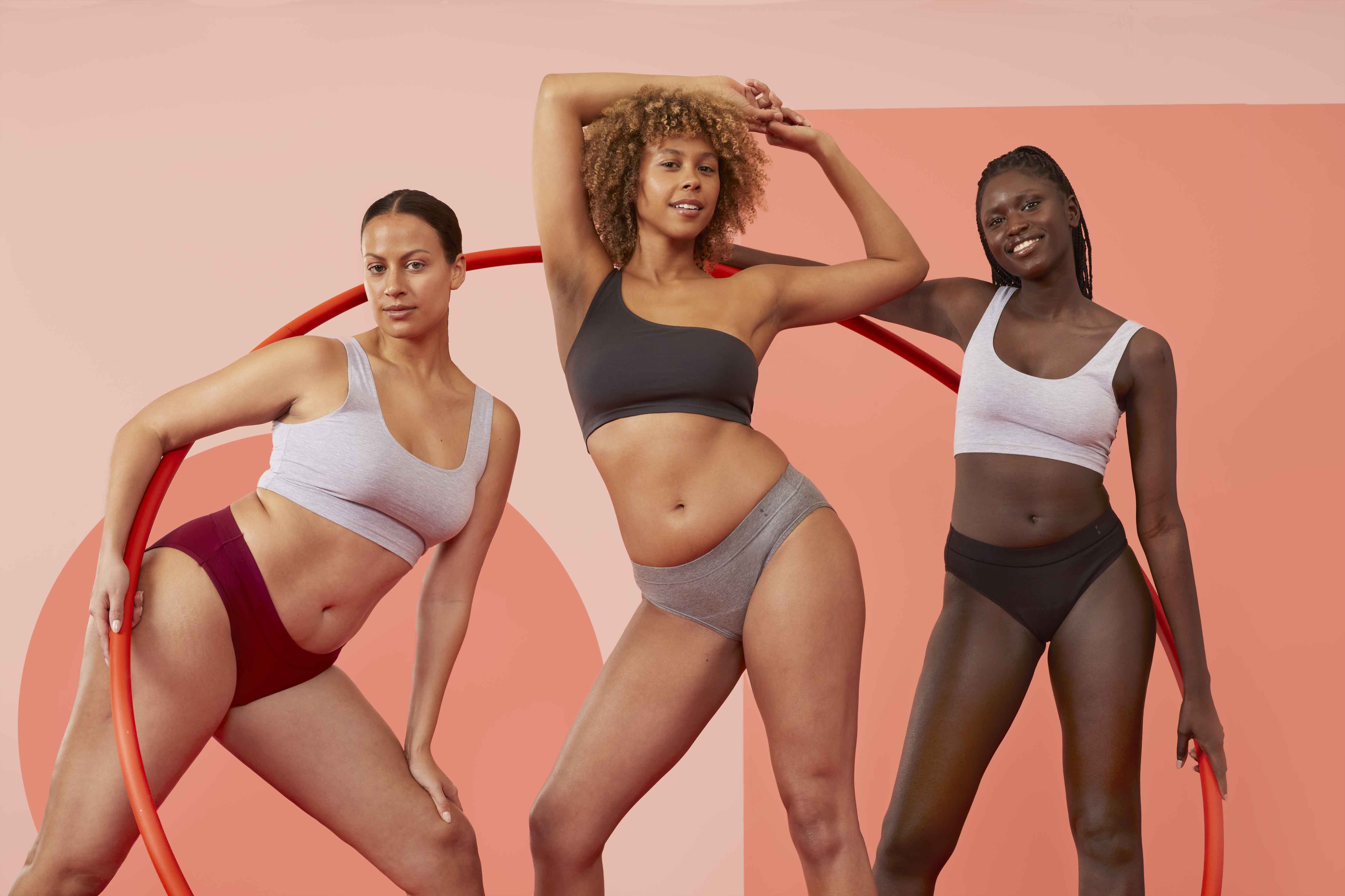 Three women standing next to each other in Thinx for All underwear smiling.